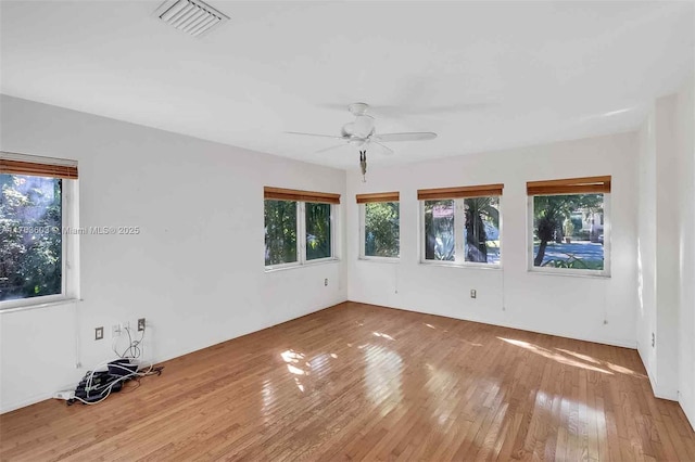 empty room with visible vents, ceiling fan, and hardwood / wood-style flooring