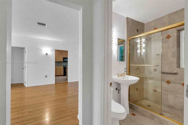 bathroom with visible vents, a shower stall, baseboards, toilet, and wood finished floors