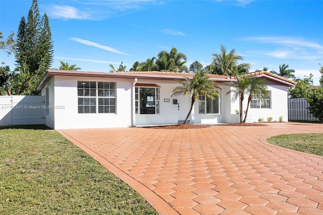 back of property with stucco siding, a tiled roof, a lawn, and fence