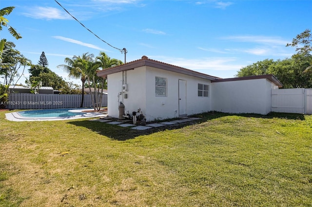 view of side of home with a fenced in pool, a yard, a fenced backyard, stucco siding, and a tiled roof