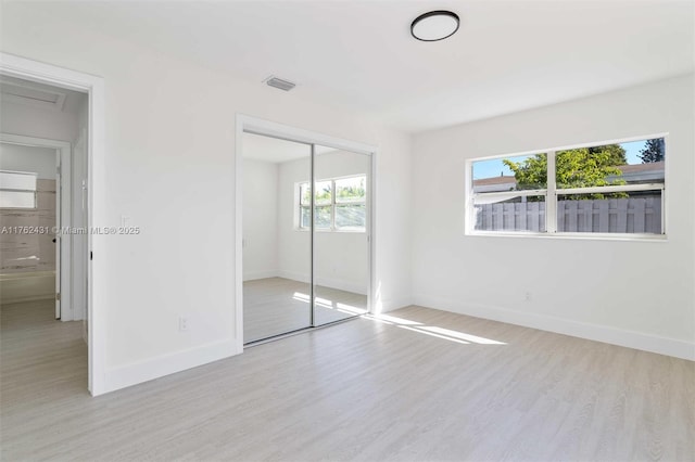 unfurnished bedroom featuring a closet, visible vents, baseboards, and wood finished floors