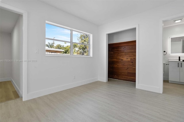 unfurnished bedroom featuring a closet, baseboards, and light wood-style floors