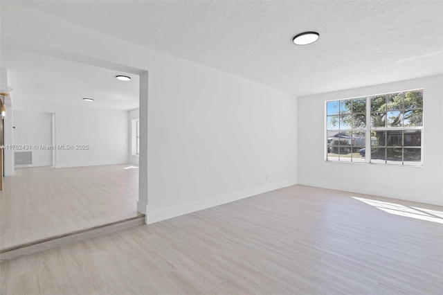 unfurnished room with wood finished floors, baseboards, and a textured ceiling