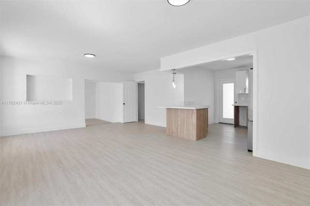 unfurnished living room with baseboards and light wood-style floors