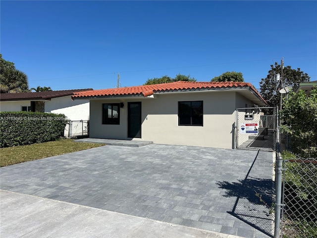 view of front of home featuring a tiled roof, fence, stucco siding, and a gate