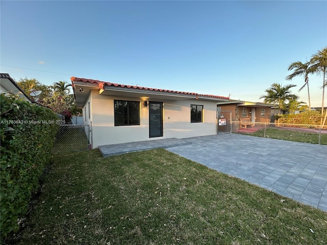 mediterranean / spanish home featuring a front yard, a tiled roof, and stucco siding