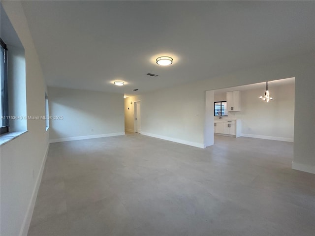 unfurnished room featuring baseboards, visible vents, and a chandelier