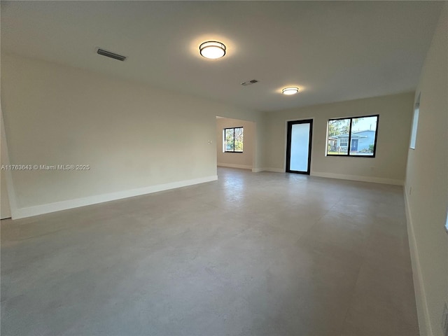 unfurnished room with finished concrete flooring, baseboards, and visible vents