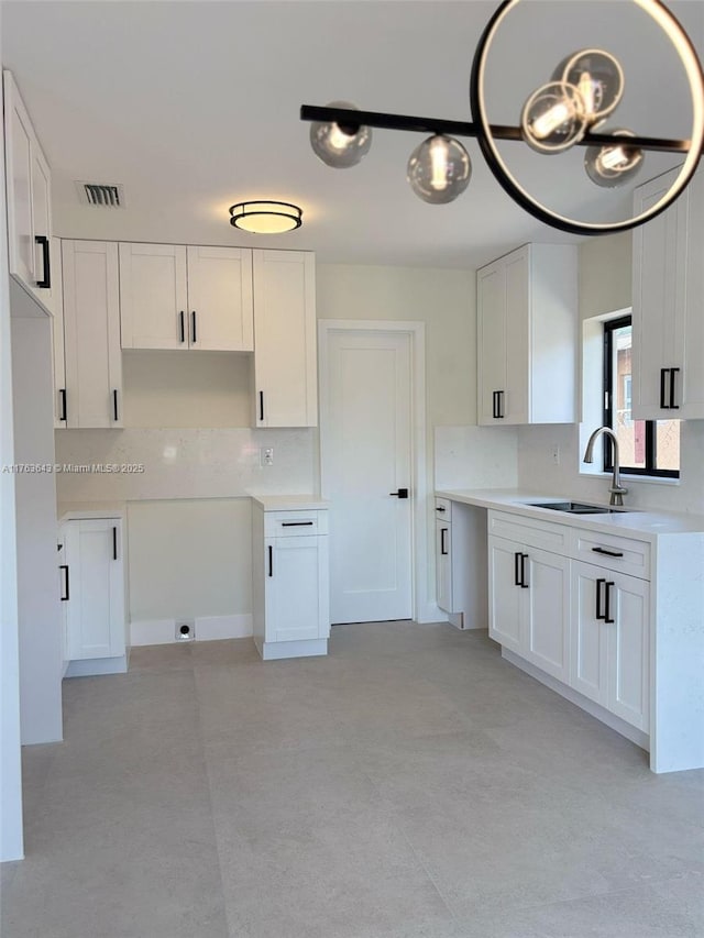 kitchen featuring visible vents, white cabinets, and a sink