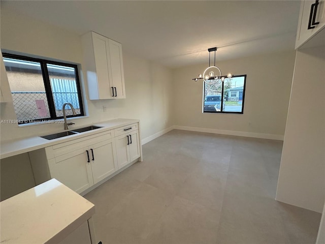 kitchen with white cabinetry, light countertops, a sink, and baseboards