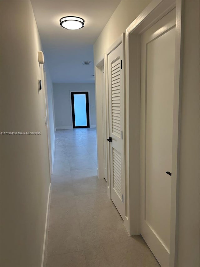 hall featuring baseboards and visible vents