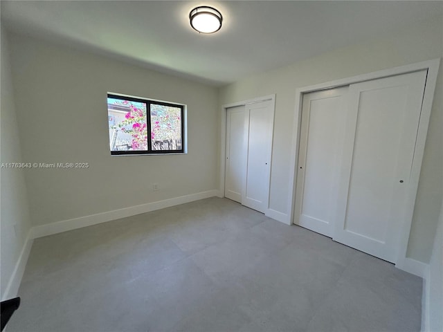 unfurnished bedroom featuring baseboards and multiple closets