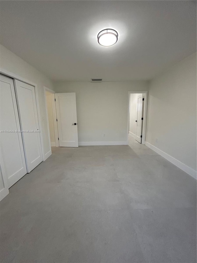 unfurnished bedroom with baseboards, visible vents, a closet, and concrete flooring