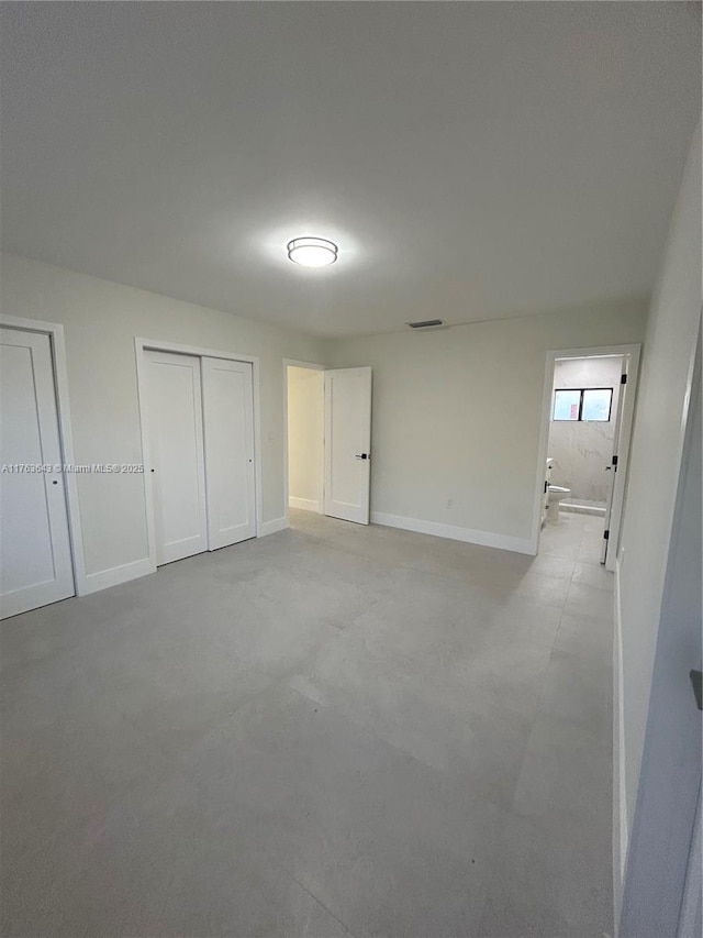 unfurnished bedroom with concrete floors, baseboards, and visible vents