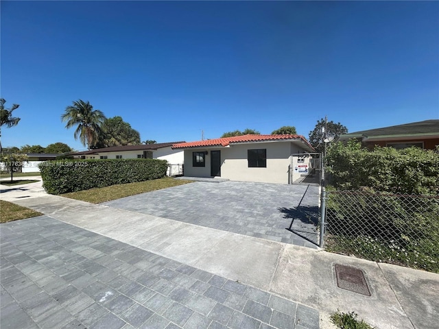 mediterranean / spanish home featuring a tile roof, a gate, stucco siding, and fence