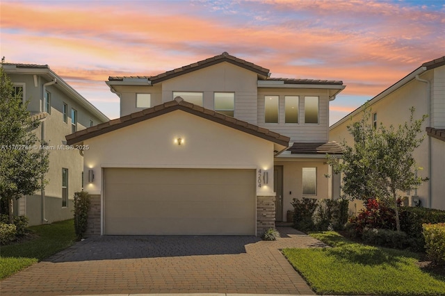 view of front of home featuring decorative driveway, a garage, stucco siding, and a tiled roof