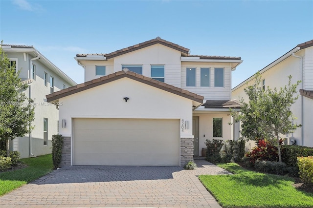 view of front facade featuring stucco siding, driveway, a tile roof, and a garage