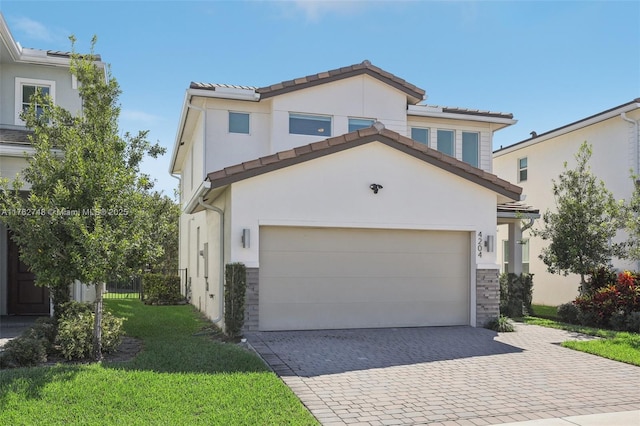 view of front of property featuring stucco siding, a front lawn, decorative driveway, stone siding, and an attached garage