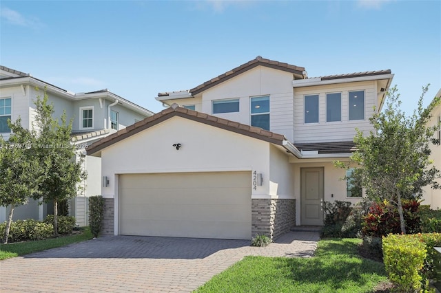 view of front of home featuring stucco siding, decorative driveway, stone siding, a garage, and a tiled roof