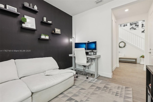 office area featuring wood finish floors, visible vents, recessed lighting, baseboards, and an accent wall