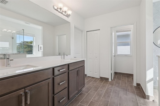 full bathroom featuring a sink, visible vents, baseboards, and double vanity