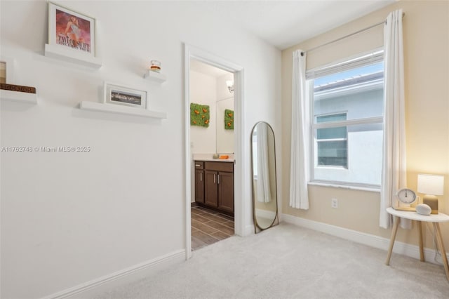 bedroom with connected bathroom, baseboards, and light colored carpet