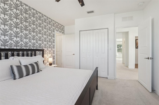 bedroom featuring wallpapered walls, visible vents, a closet, and light carpet