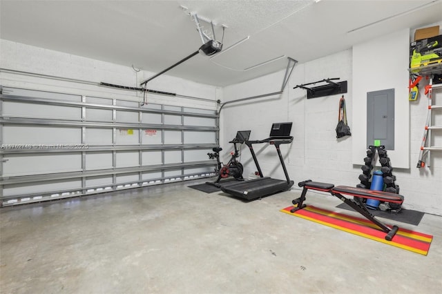 exercise area with electric panel, a garage, and concrete block wall