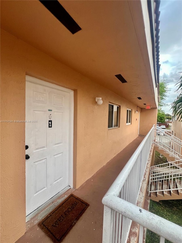 view of exterior entry featuring stucco siding and a balcony