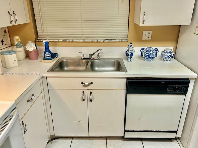 kitchen with light countertops, white cabinets, white dishwasher, and a sink