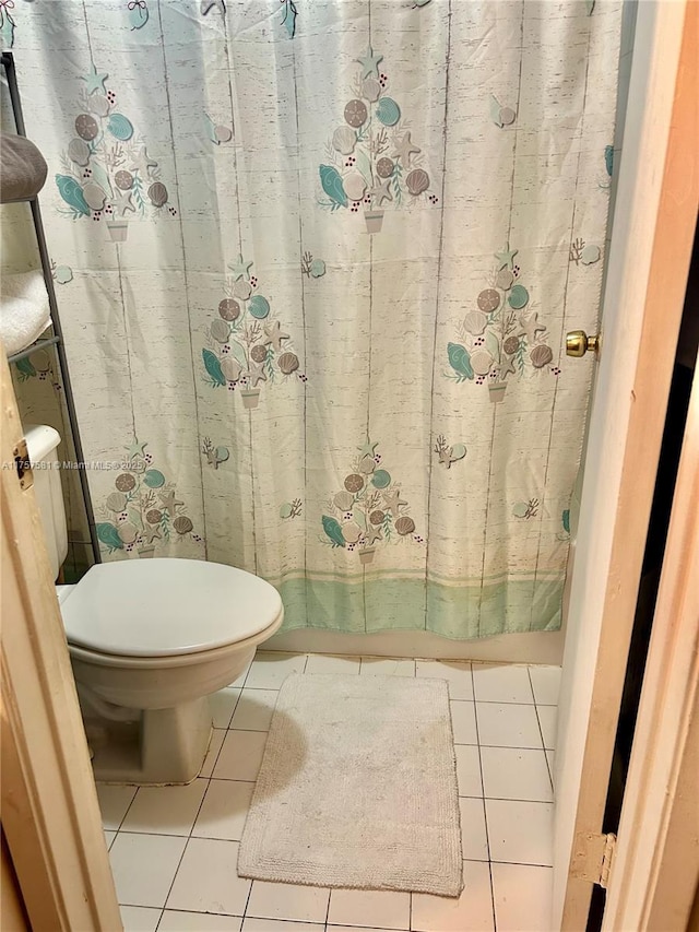 bathroom featuring tile patterned flooring, a shower with shower curtain, and toilet