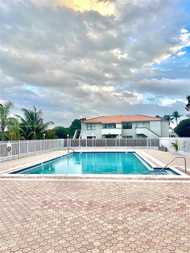 pool with a patio area and fence