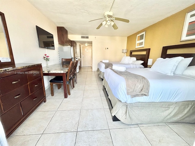 bedroom featuring visible vents, a ceiling fan, a textured ceiling, freestanding refrigerator, and light tile patterned floors