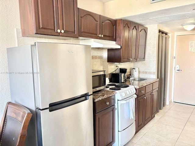 kitchen featuring a sink, under cabinet range hood, tasteful backsplash, stainless steel appliances, and light tile patterned floors