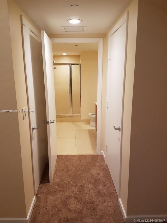 corridor featuring tile patterned floors, carpet, and baseboards