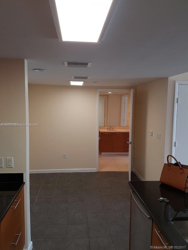 kitchen featuring visible vents, a sink, dark countertops, tile patterned flooring, and baseboards