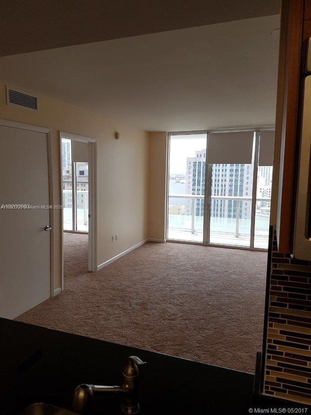 carpeted spare room with visible vents and baseboards