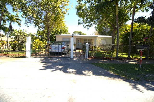 view of front of house featuring a fenced front yard, stucco siding, driveway, and a gate