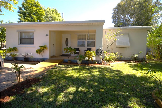 view of front of house with covered porch, a front lawn, and stucco siding