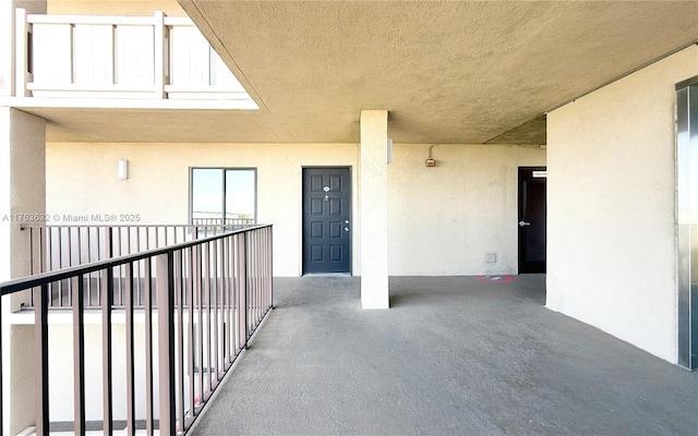 property entrance with stucco siding and a balcony