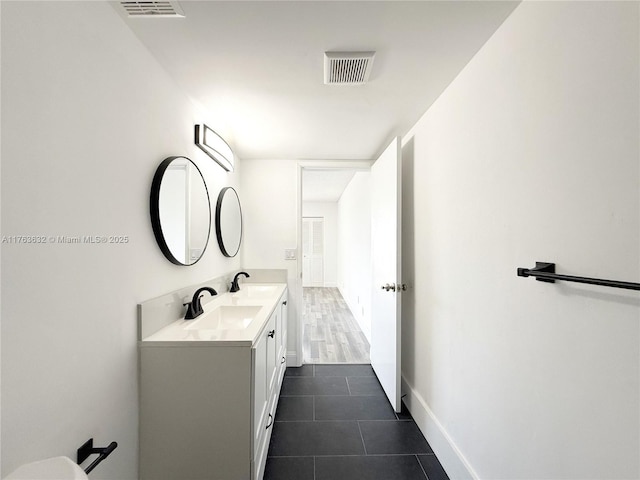 bathroom featuring tile patterned flooring, double vanity, visible vents, and a sink