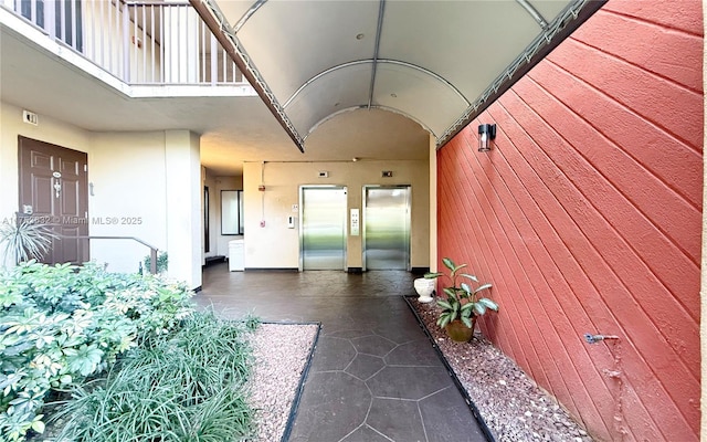 entrance to property featuring elevator and a balcony