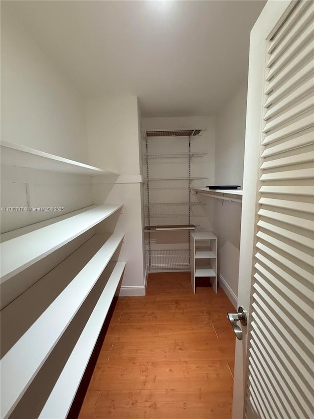 walk in closet with wood finished floors