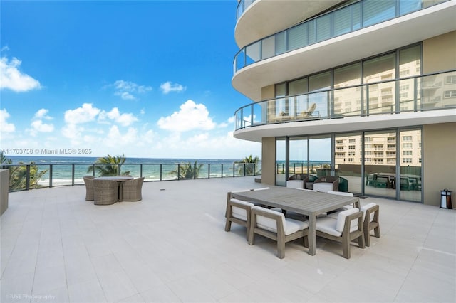 view of patio featuring outdoor dining space, a beach view, and a water view