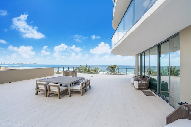 view of patio / terrace with a beach view, a balcony, and a water view