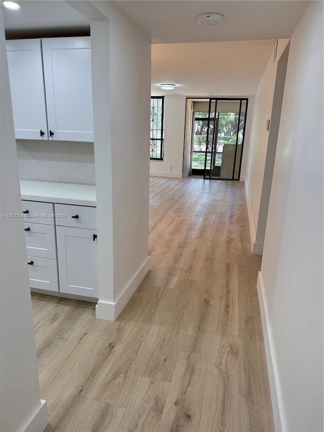 hallway with light wood-type flooring and baseboards