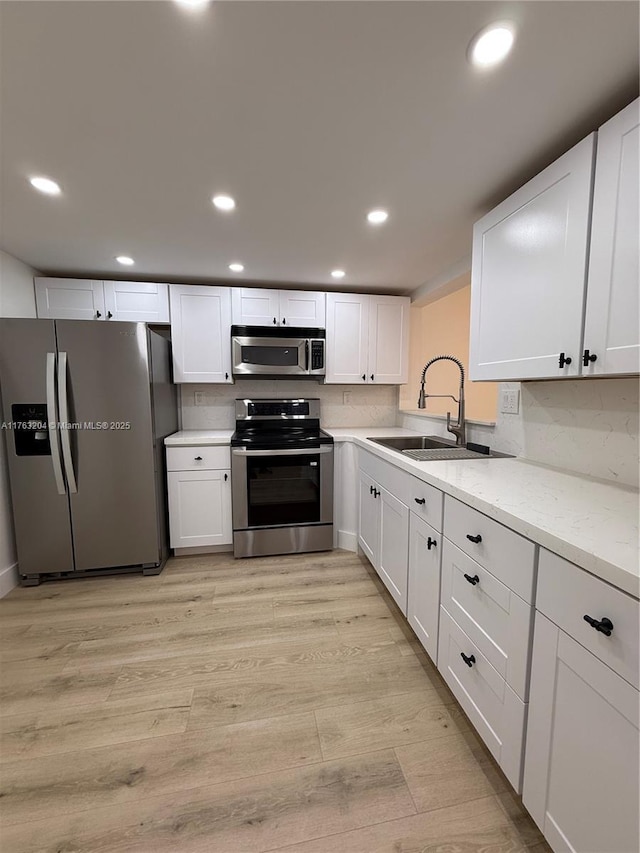 kitchen with recessed lighting, light wood-style floors, appliances with stainless steel finishes, and a sink