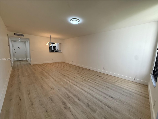 empty room with baseboards, visible vents, and light wood finished floors