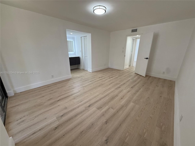 unfurnished room featuring light wood-style floors, visible vents, and baseboards