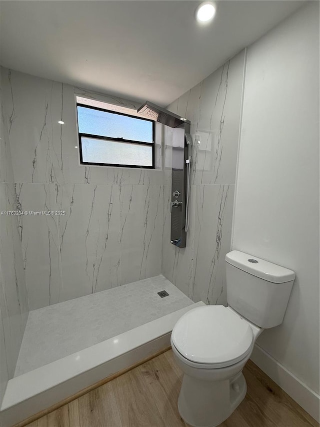 full bathroom featuring toilet, wood finished floors, baseboards, and a marble finish shower